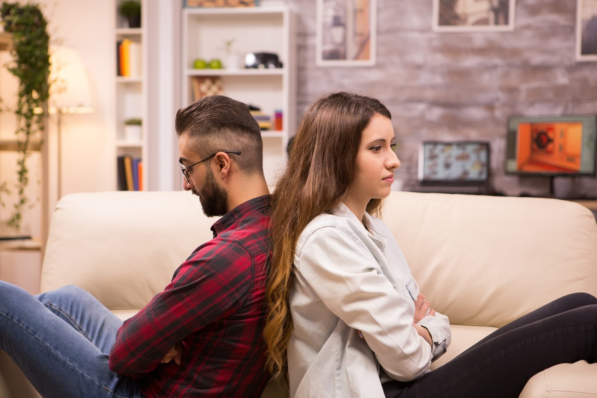 Caucasian couple sitting back to back with serious relationship