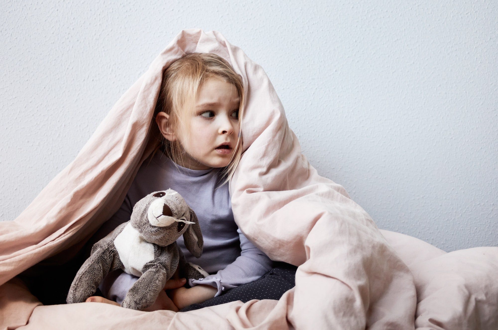 Little scared girl hiding under cover of warm blanket, war, aggression, home violence, health